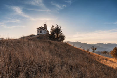 Church on field by building against sky