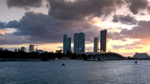 Scenic view of sea by buildings against sky during sunset