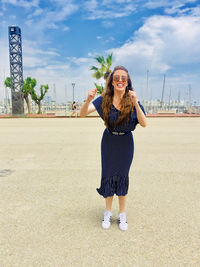 Portrait of smiling young woman standing against sky