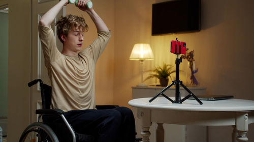 Young man exercising while sitting on wheelchair