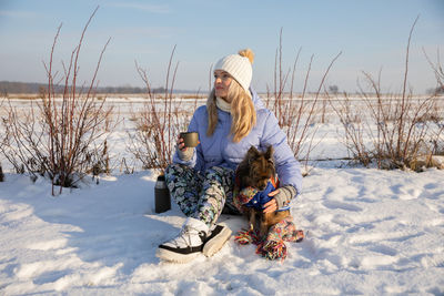 Rear view of woman sitting on snow covered field