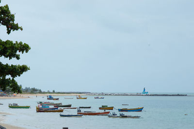 Boats moored in sea against clear sky