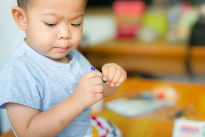 Boy with crayon on table at home
