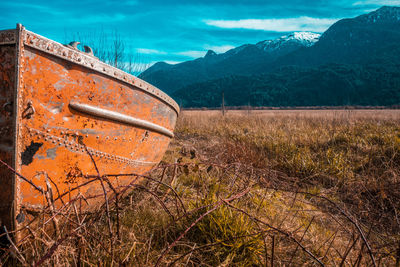 Abandoned car on field against sky