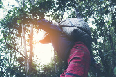 Person carrying sack on back while walking by trees 