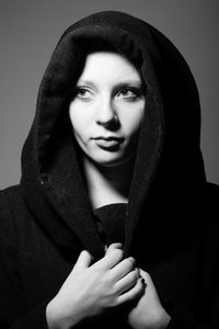 Close-up of young woman looking away against gray background