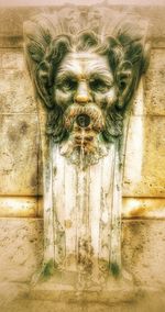 Close-up of old statue against wall