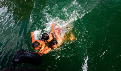 High angle view of male friends swimming in sea