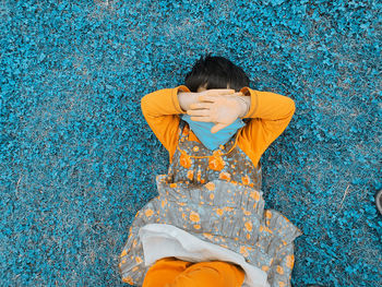 Woman with umbrella standing against blue wall