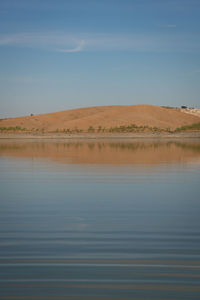 Desert like hill landscape with reflection on the water on a dam lake reservoir in terena, portugal