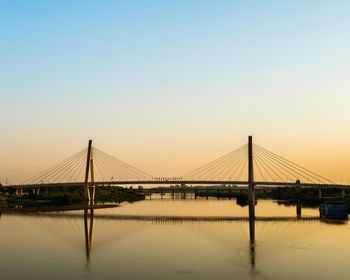 Suspension bridge over river against clear sky