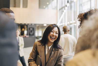 Laughing female entrepreneur discussing with delegates during networking event at convention center