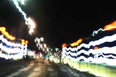 Defocused image of illuminated lights on road at night