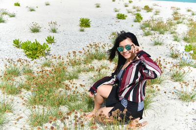 Portrait of young woman wearing sunglasses standing against plants