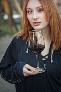 Portrait of young woman holding red wine in glass