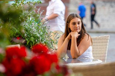 Young woman looking away while sitting at cafe outdoors