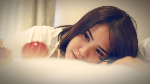 Close-up of thoughtful beautiful woman lying on bed at home