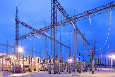 Illuminated electricity substation at dusk.