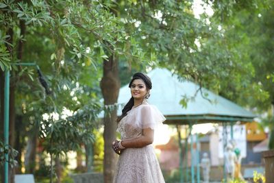 Smiling young woman standing against trees