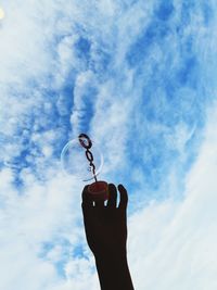 Low angle view of person hand making bubbles against sky