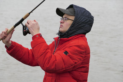 A young man, a fisherman in bright clothes, catches fish with a fishing rod. high quality photo