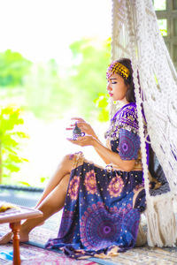 Side view of woman sitting outdoors