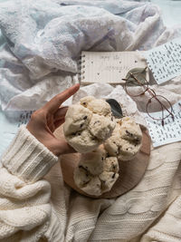 Close-up of hand holding book on bed