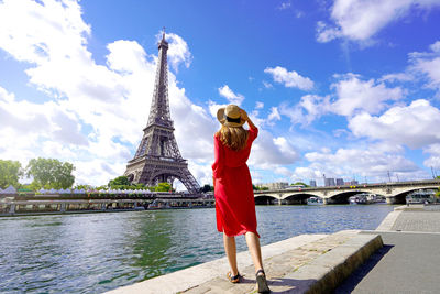 Back view of young woman visiting the city of paris with eiffel tower and seine river.