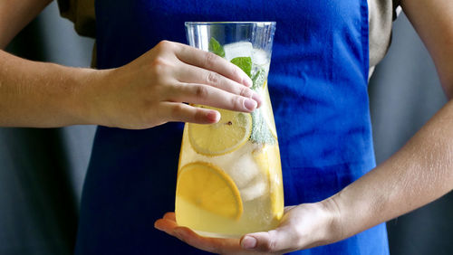 Lemon lemonade with mint, lemon and ice in a carafe.