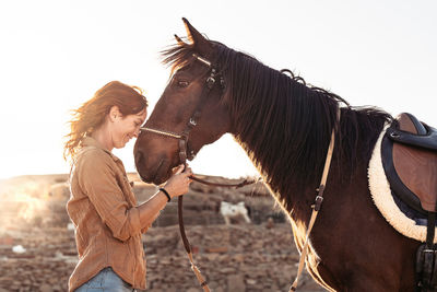 Side view of woman standing by horse