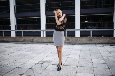 Portrait of confident woman standing on street against building in city