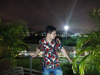 Portrait of young woman standing against sky at night