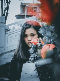 Portrait of beautiful young woman standing against window