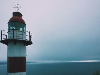 Lighthouse by lake against sky in foggy weather