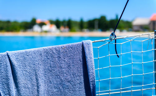 Close-up of towel hanging on netting by sea