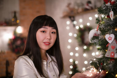 Portrait of young woman against christmas tree