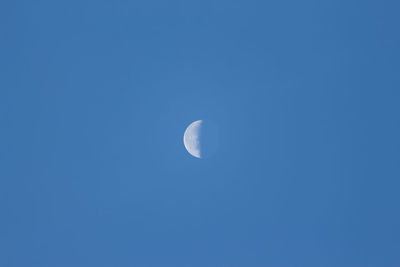 Low angle view of moon against blue sky