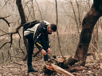 Man standing by bare trees in forest