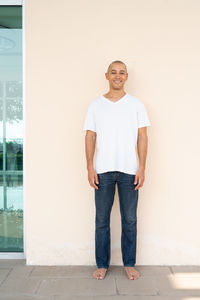 Portrait of young man standing against wall