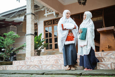 Mother and daughter in hijab standing outside home