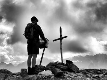 Man standing on rock against cloudy sky