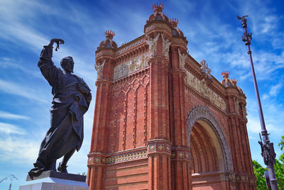 Low angle view of statue of historic building against cloudy sky