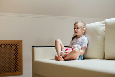 Full length of woman sitting on sofa at home