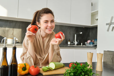 Portrait of young woman holding apple on table