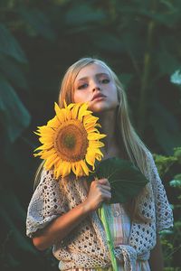 Close-up portrait of young woman with sunflower