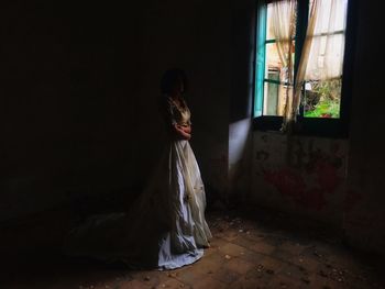 Woman standing on window in abandoned room