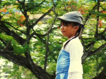 Young woman standing against tree