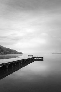 Parkbench on a wooden jetty at the lake wallersee, austria.