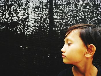 Close-up of boy against fence