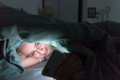 Portrait of young woman resting on bed at home